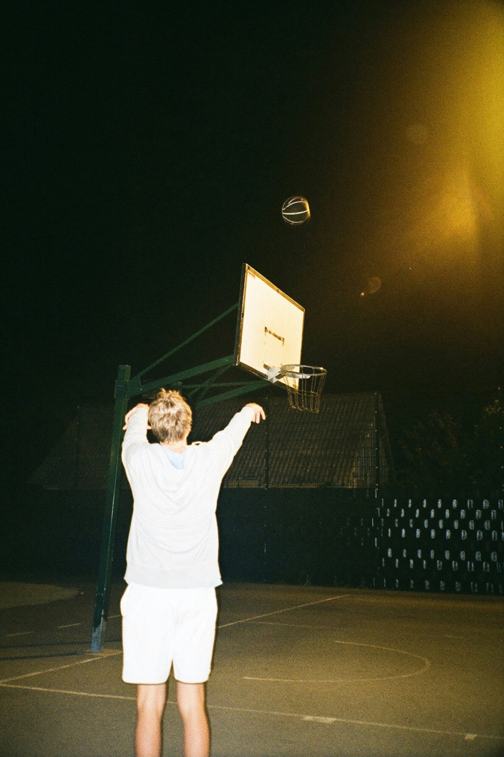 Basketball player shooting a ball on a professional court.